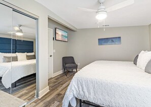 Ein Schlafzimmer mit einem großen Bett, einem Sessel, einem Fernseher und einem Deckenventilator.