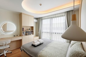 Ein modernes Hotelzimmer mit Bett, Nachttisch, Schreibtisch, Stuhl und einem großen Fenster mit Vorhängen.
