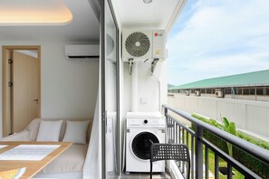 A balcony with a washing machine, a chair, and a fan. - Kamala - Peaceful Jungle View (Tambon Kamala)