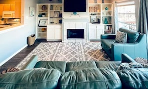Una sala de estar con chimenea, televisor y sofá.