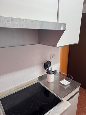 A kitchen with a black induction cooktop, a stainless steel range hood, and a white tiled backsplash. - Gandia Beach, First-Line Beachfront (Grau i Platja)