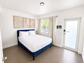 Ein Hotelzimmer mit einem Bett, einer Tür mit WLAN-Hinweis und einem Fenster mit Vorhängen.