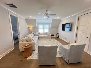 A spacious living room with a sectional sofa, a grey armchair, a small side table, and a ceiling fan. - Spacious 4-bedroom house on the Country Club. Less than 2mi from the stadium! (Oxford)