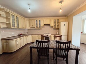 Une cuisine équipée d’une table et de chaises, de meubles de rangement en bois, d’une cuisinière et d’un réfrigérateur.