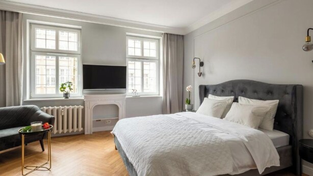 A hotel room with a bed, a television, a sofa, and a radiator. - Długa - Stare Miasto by Grand Apartments (Gdańsk)