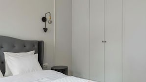 A bedroom with a bed, a nightstand, a wall-mounted lamp, and a wardrobe. - Długa - Stare Miasto by Grand Apartments (Gdańsk)