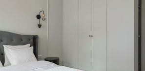 A bedroom with a bed, a nightstand, a wall-mounted lamp, and a wardrobe. - Długa - Stare Miasto by Grand Apartments (Gdańsk)