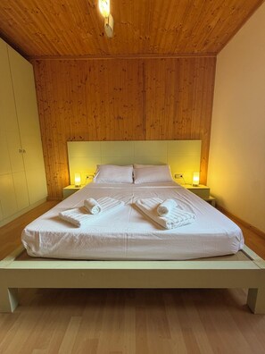 A single-bed room with wooden panel walls, a white bedspread, and bedside lamps. - Casa Bolets - A house in the woods near the best beaches in southern Catalonia (L'Ametlla de Mar)