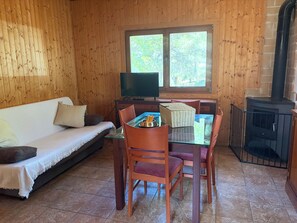 A wooden interior with a sofa, dining table, chairs, a television, and a fireplace. - Casa Bolets - A house in the woods near the best beaches in southern Catalonia (L'Ametlla de Mar)