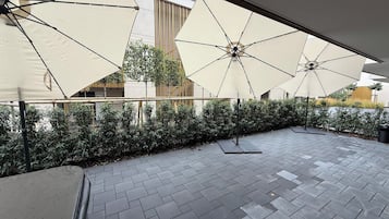 An outdoor patio area with tiled flooring and multiple large umbrellas providing shade.