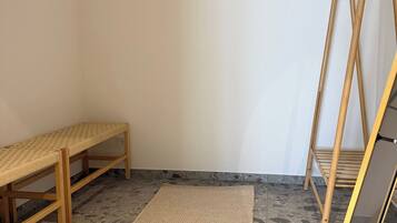 A room with a bench, a mat, a wooden stand, and a window.