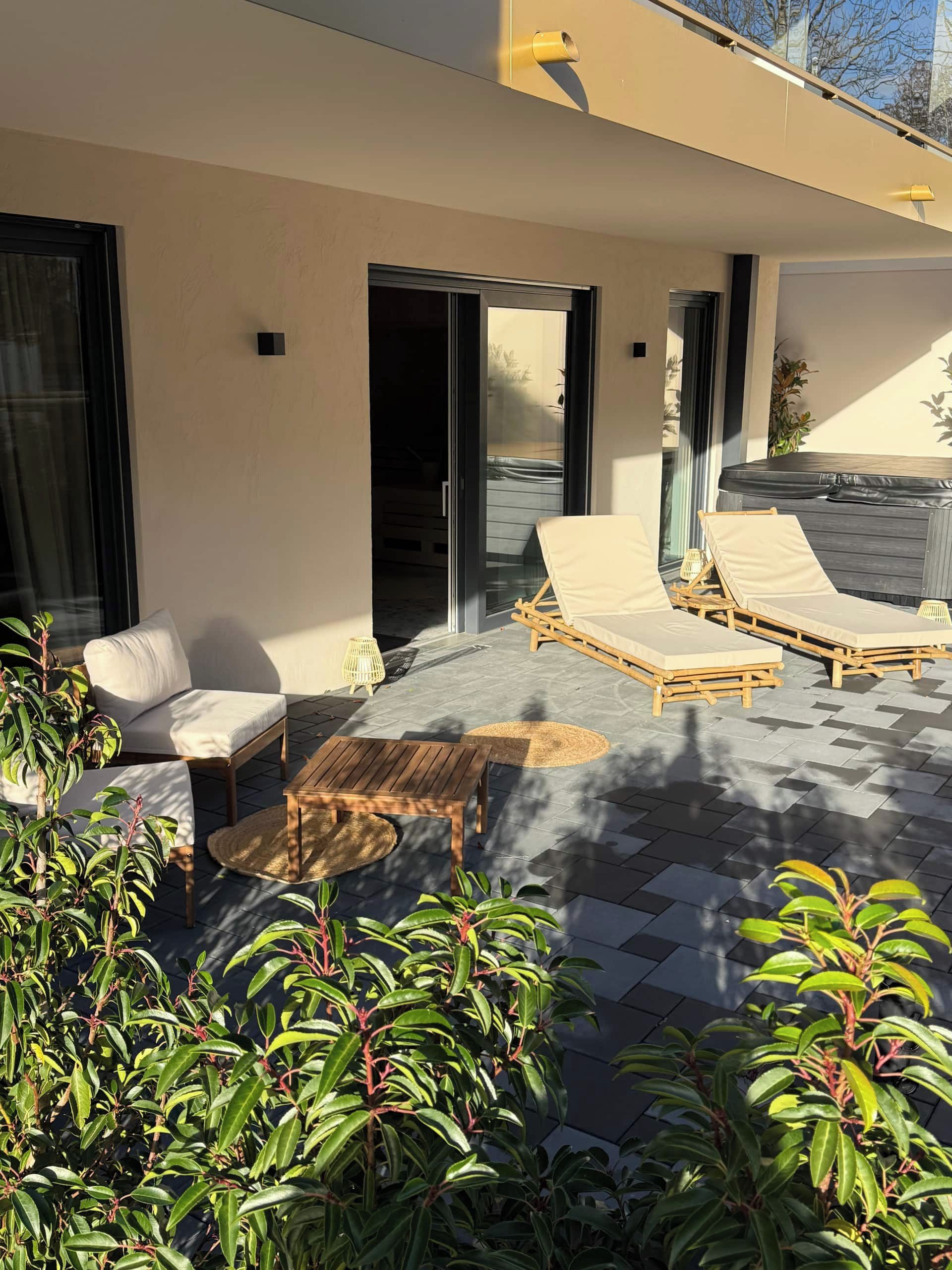 Een moderne buitenruimte met lounge fauteuils en een bijzettafeltje.