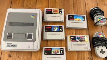 Una consola Super Nintendo Entertainment System con varios cartuchos sobre una superficie de madera.