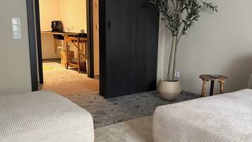 A room with two sofas, a potted plant, and a sliding door leading to another room.