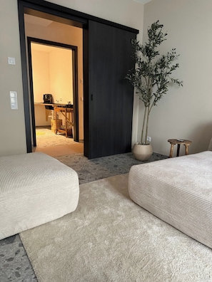 A room with two sofas, a potted plant, and a sliding door leading to another room. - KaiserLogen Wellness — a private spa oasis with an XXL sauna and outdoor hot tub (Kaisersesch)