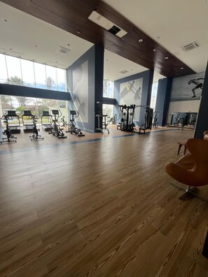 A spacious gym with various exercise equipment, large windows, and a wooden floor. - Beachfront 2-Bedroom Condo, Ocean and Island Views, Jacuzzi – Mazatlán (Mazatlán)