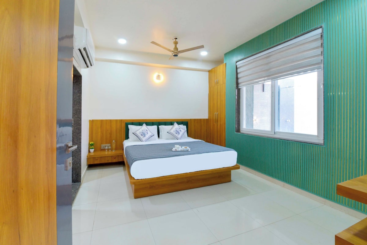 A bedroom with a bed, a ceiling fan, a window with blinds, and a green wall.