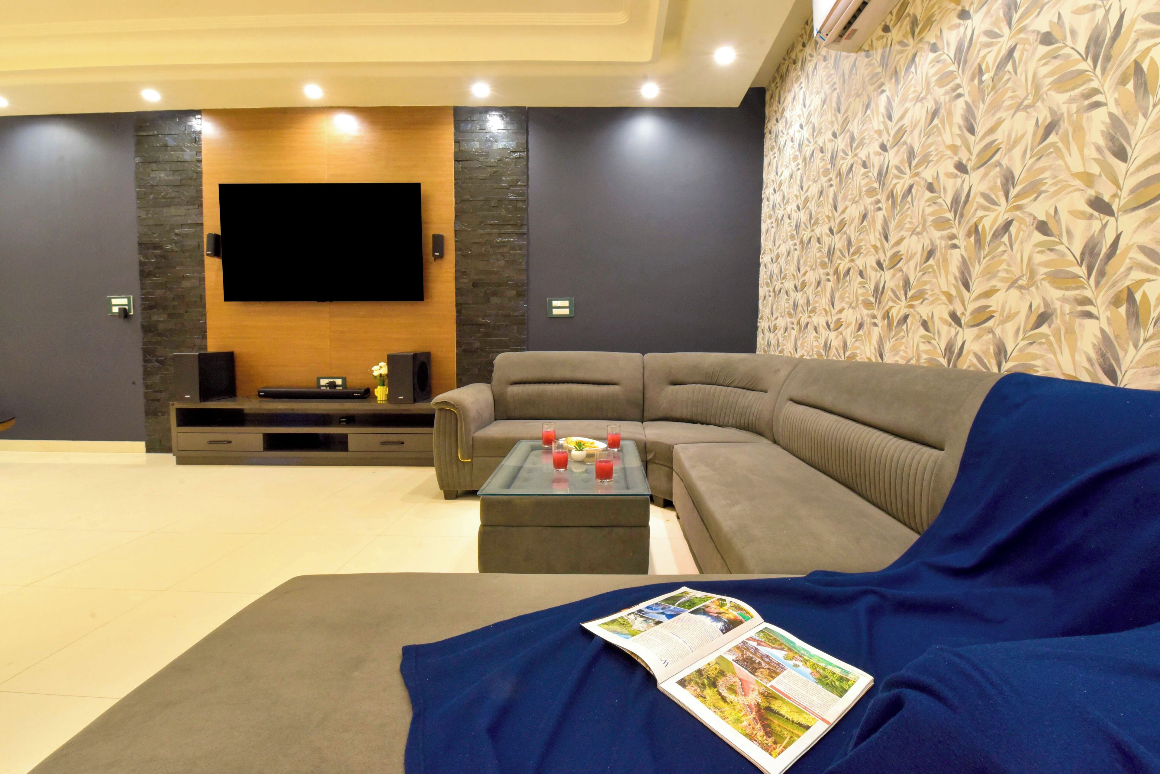 Una sala de estar moderna con un sofá modular, un televisor de pantalla plana y una mesa de centro.