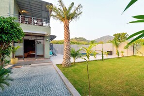 A modern building with a covered outdoor area, a palm tree, and a pool with a patterned floor.