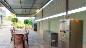 An outdoor patio area with a table and chairs, a grill, and a refrigerator. - DanCenter Hill's Stay Villa 3BHK (Kishangarh)