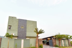 Un edificio moderno con techo plano, un elemento vertical central y una zona exterior cubierta con asientos.