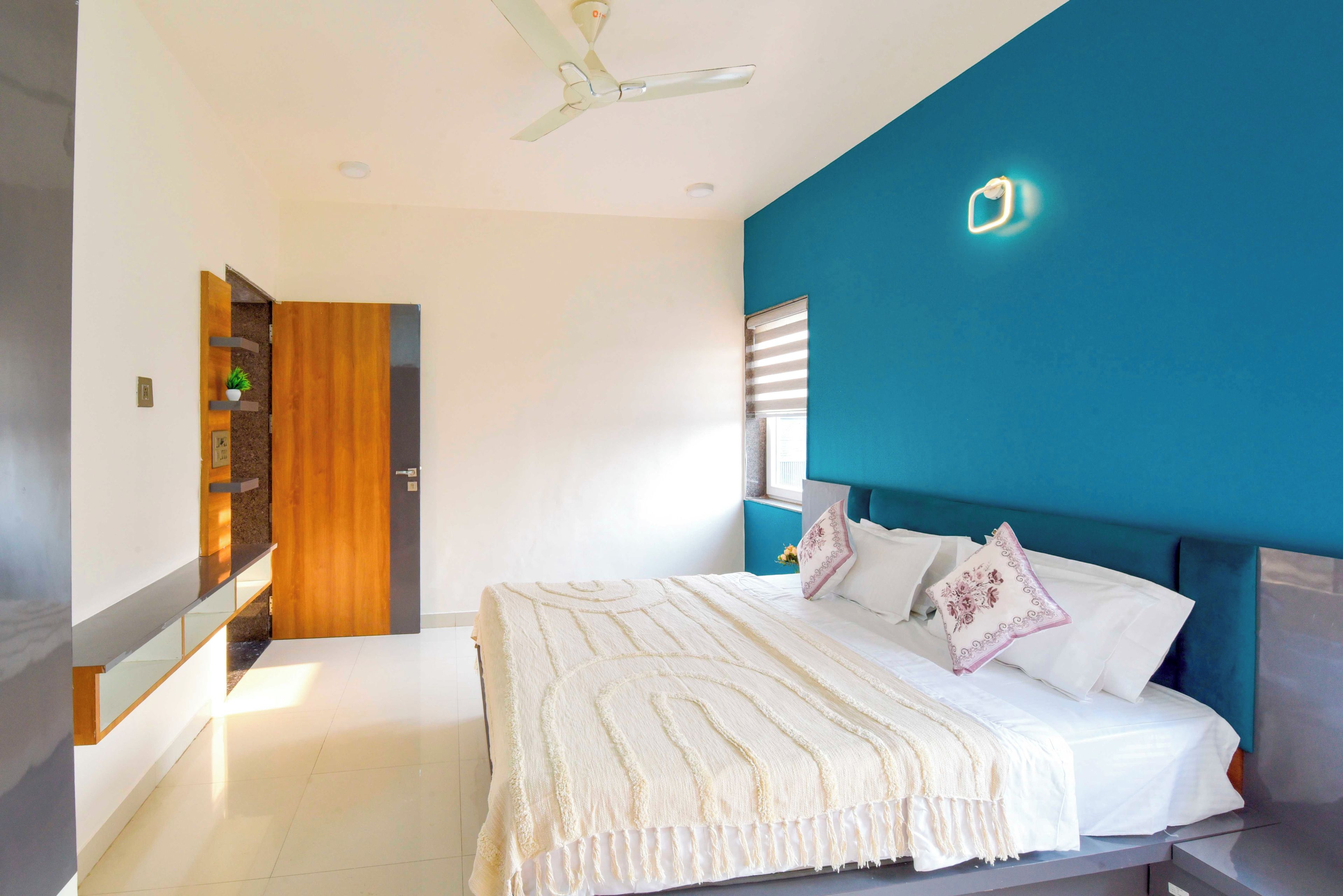 Un dormitorio con una cama, ventilador de techo, mesita de noche y una lámpara de pared.