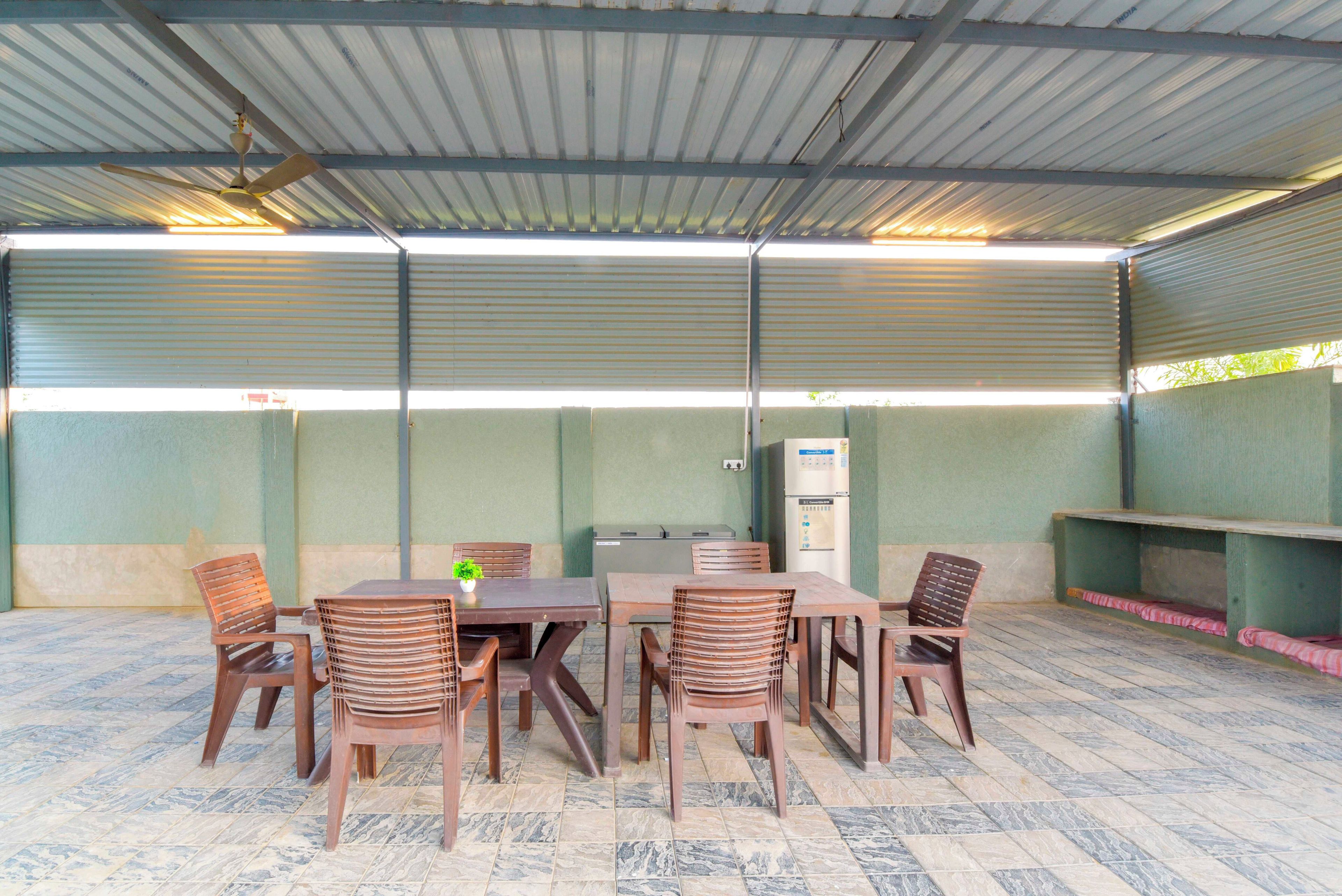 An outdoor covered area with a table and chairs, a vending machine, and a ceiling fan.