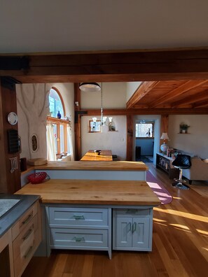 Een keuken met houten kastjes, een centraal eiland en een eethoek met een tafel en stoelen.
