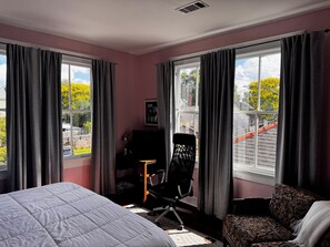 A hotel room with a bed, a desk, a chair, and large windows with curtains. - Charming 3-Bed Algiers Pt Gem- Steps from FQ ferry (New Orleans)