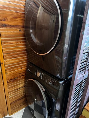 A stacked washer and dryer unit with a wooden panel wall and a tiled floor. - Charming 3-Bed Algiers Pt Gem- Steps from FQ ferry (New Orleans)