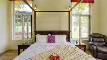 A bedroom with a bed, a chair, and two windows with curtains.