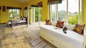 Quarto com cama, sofá e amplas janelas.