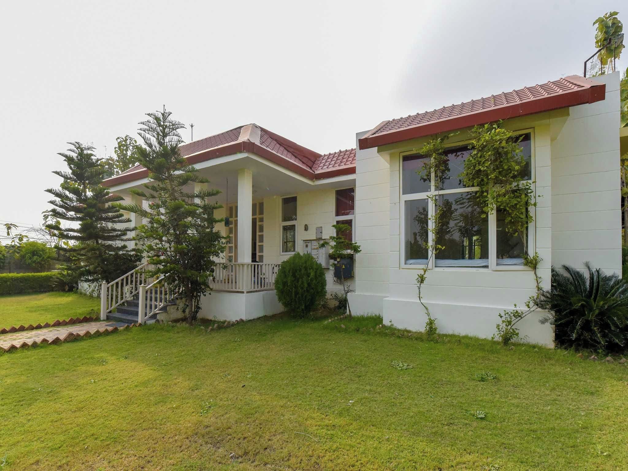 A two-story building with a covered porch and a small garden area.