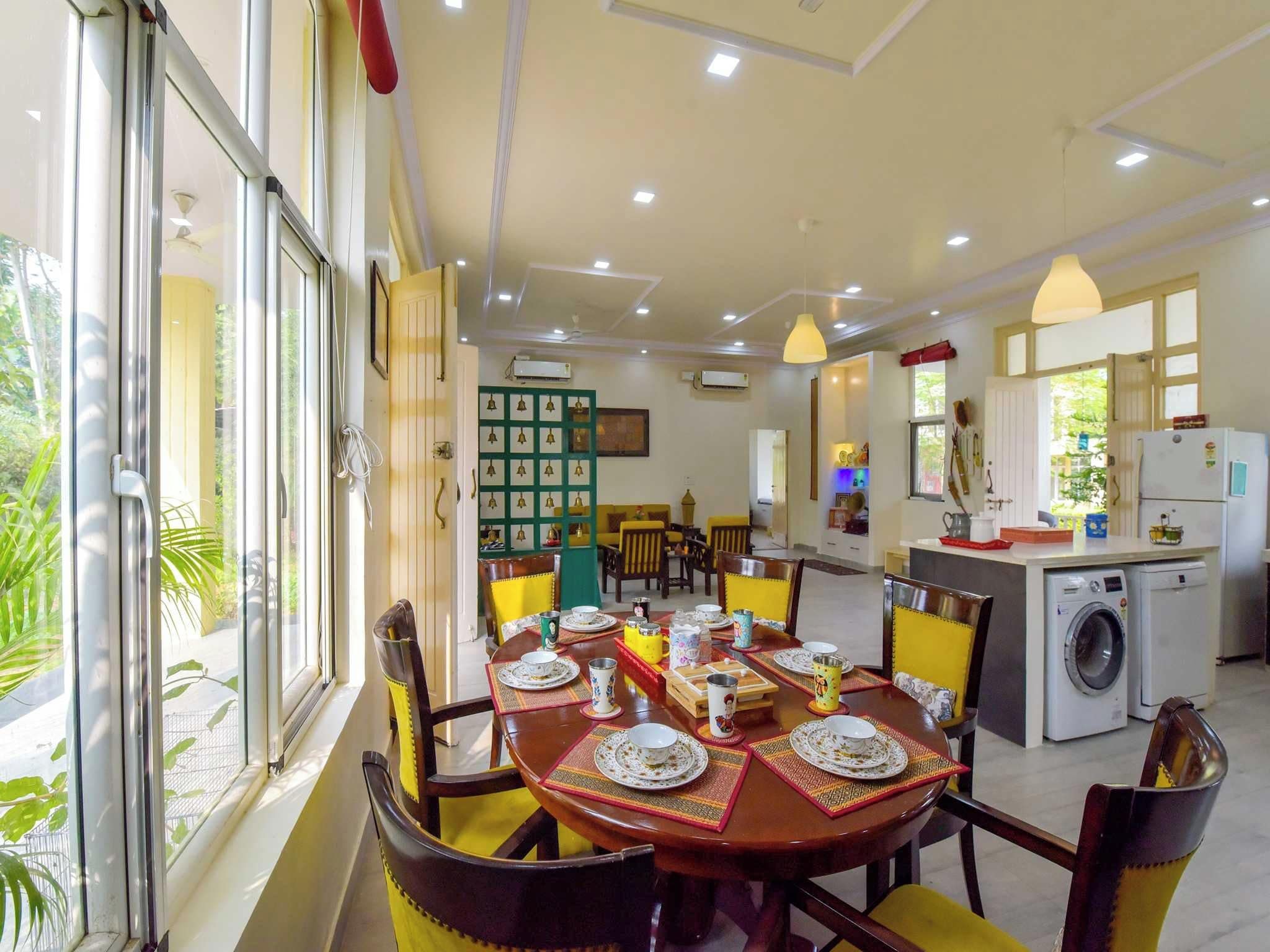 Un comedor con mesa lista para cuatro, una cocina equipada con lavadora y vistas a zonas verdes.