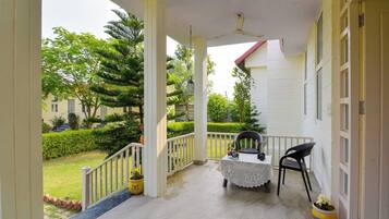 A covered porch with a table and chairs, a ceiling fan, and potted plants.