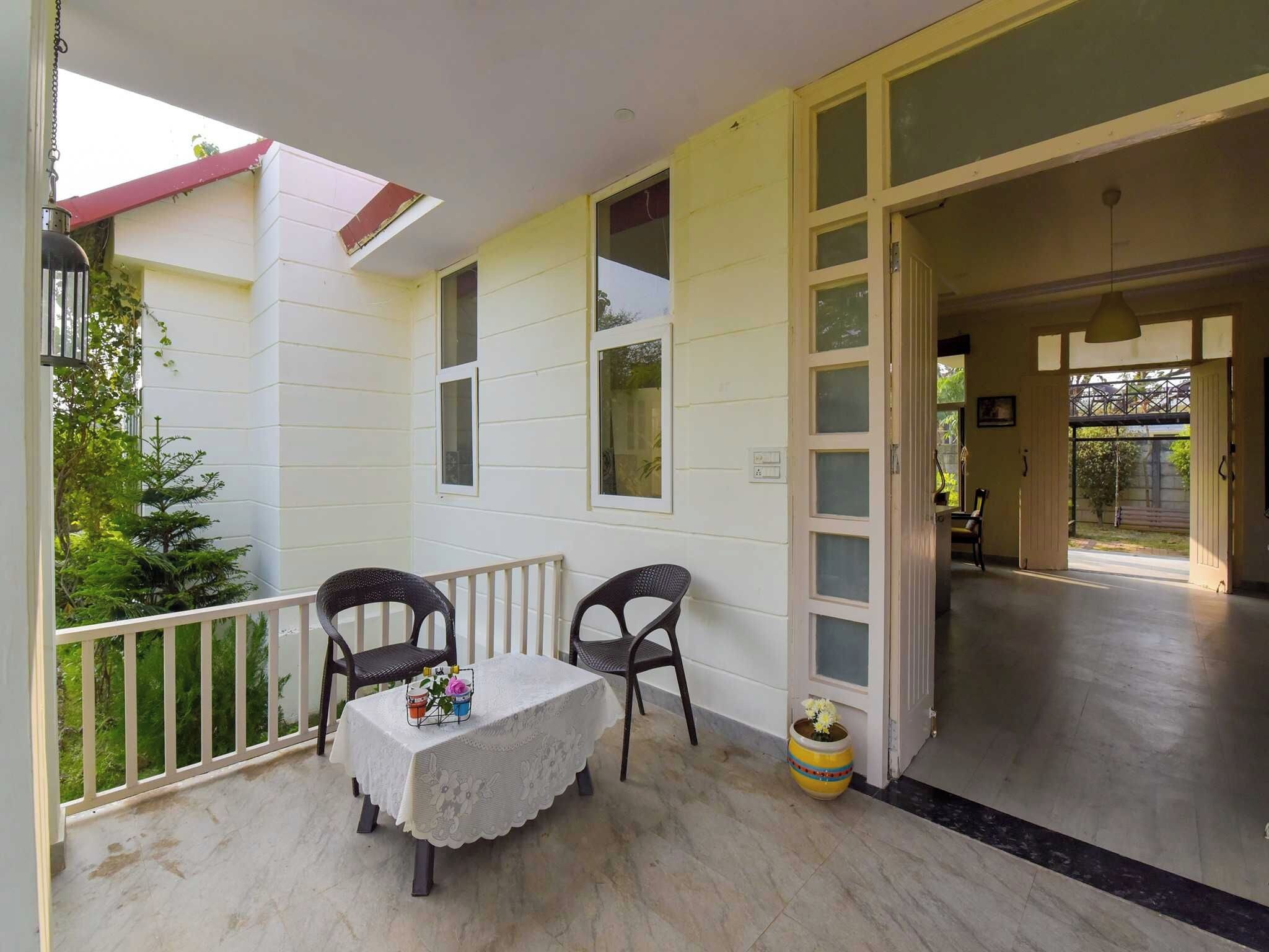 A balcony with a table and chairs, a potted plant, and a view of the outside.