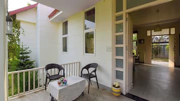 A balcony with a table and chairs, a potted plant, and a view of the outside.