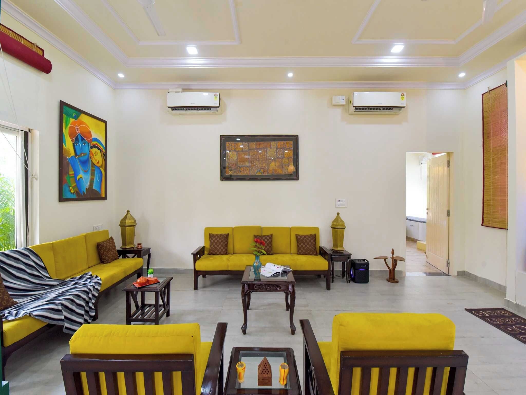A living room with a yellow sofa set, a coffee table, and a painting on the wall.