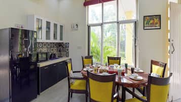 A dining area with a table set for four, surrounded by chairs with yellow cushions.