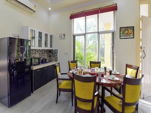 Comedor con una mesa dispuesta para cuatro personas, rodeada de sillas con cojines amarillos.