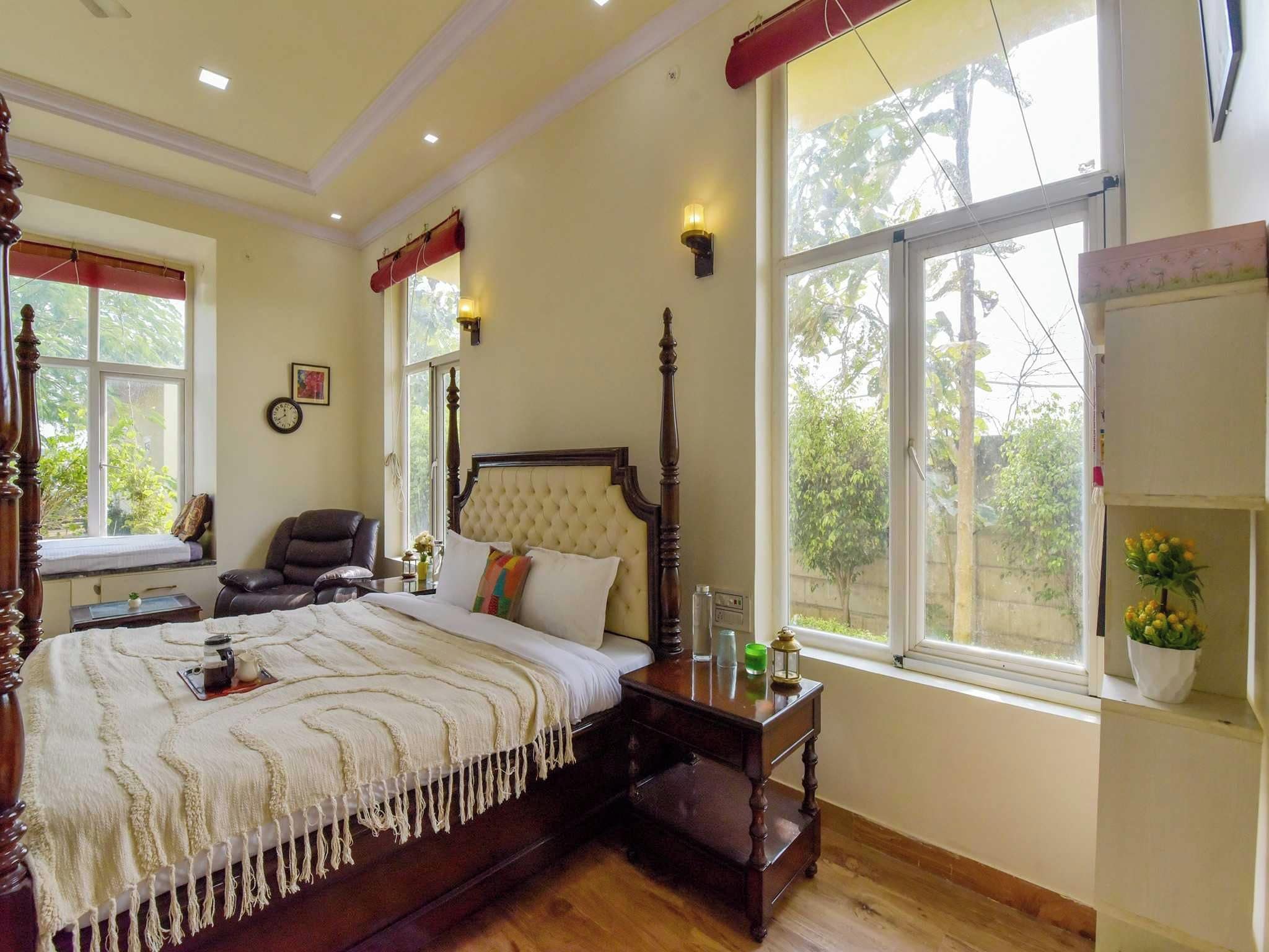 Un dormitorio tradicional con cama con dosel, una mesita de noche de madera, una silla y una ventana con vistas a zonas verdes.