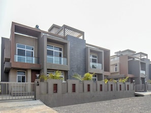 A modern multi-story residential building with a flat roof, large windows, and a concrete facade.