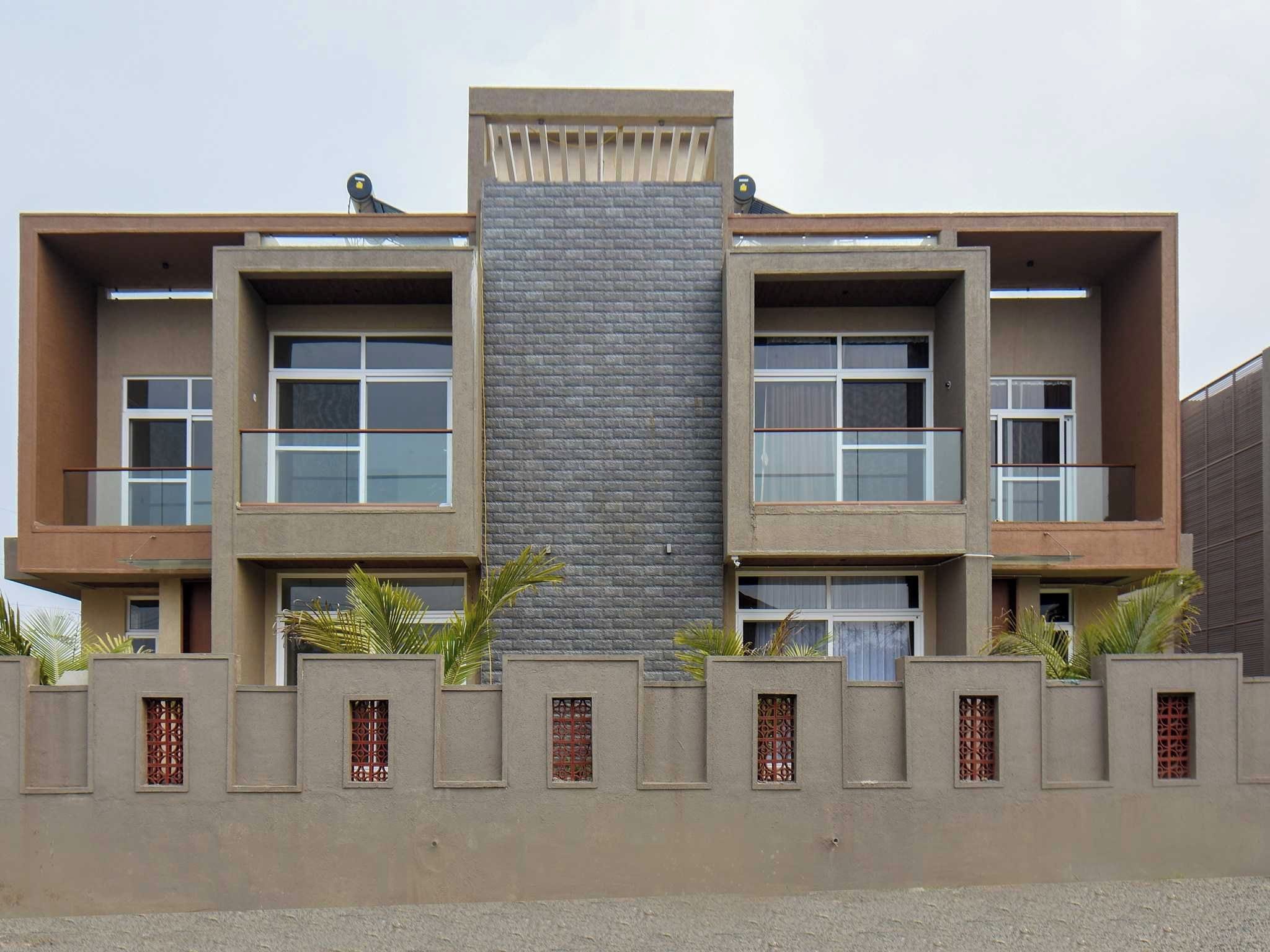 A modern two-story building with a central glass facade, balconies on each floor, and decorative metal grilles on the lower facade.