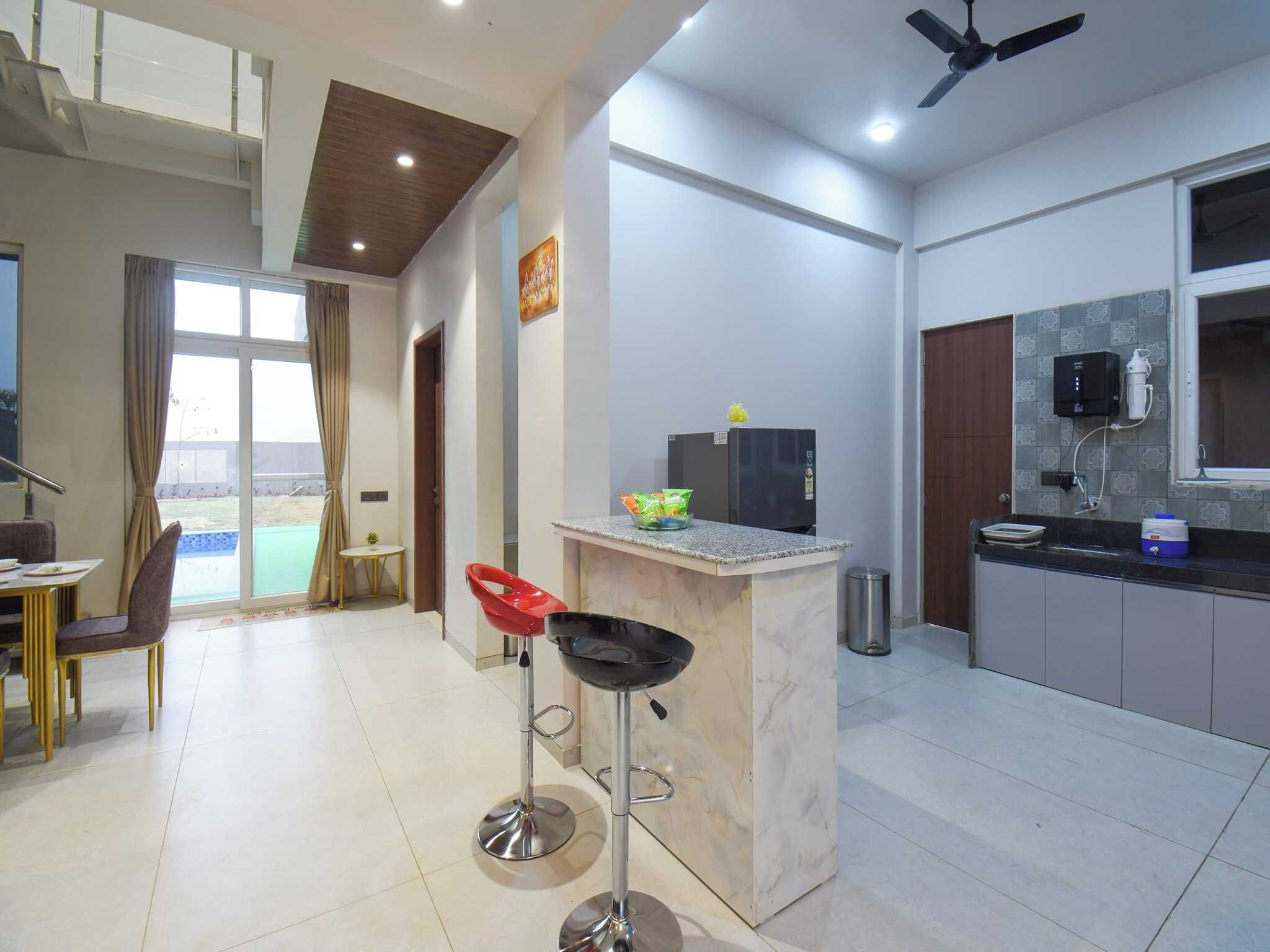 A modern kitchen with a built-in stove, a small island with bar stools, and a dining area with a table and chairs.
