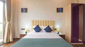 A hotel room with a large bed, two bedside tables with lamps, a headboard, and two paintings on the walls.