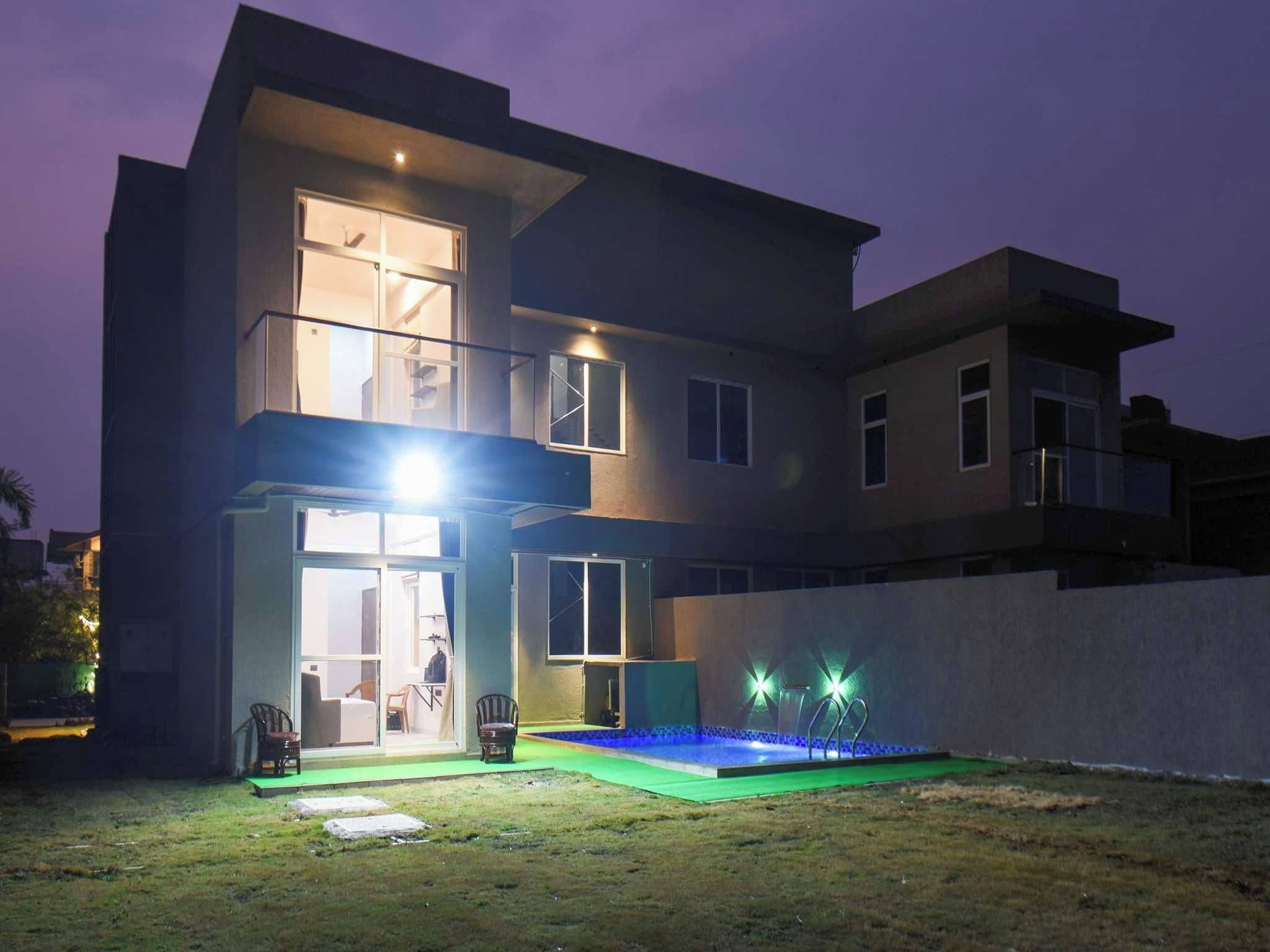 A modern two-story house with a swimming pool, large windows, and a balcony.