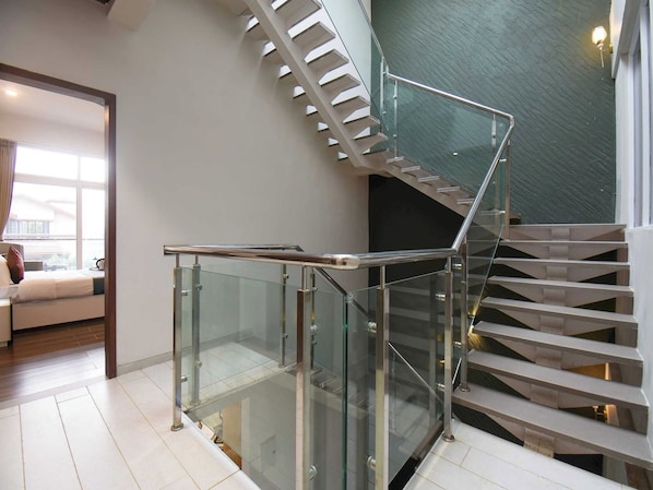 A modern interior with a glass railing staircase, a sofa, and a view through the glass.