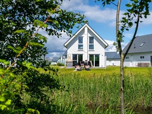 A two-story house with a large front lawn and a patio area with outdoor furniture. - NEW - Beach Lodge (Kappeln)