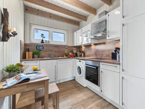 A modern kitchen with white cabinetry, a wooden countertop, a built-in oven, and a washing machine. - NEW - Beach Lodge (Kappeln)