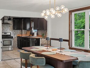A modern kitchen with dark cabinets, a stainless steel stove, and a large island with seating. - Point Gratiot Lake House, Sleeps 12+, Lake Views (Dunkirk)